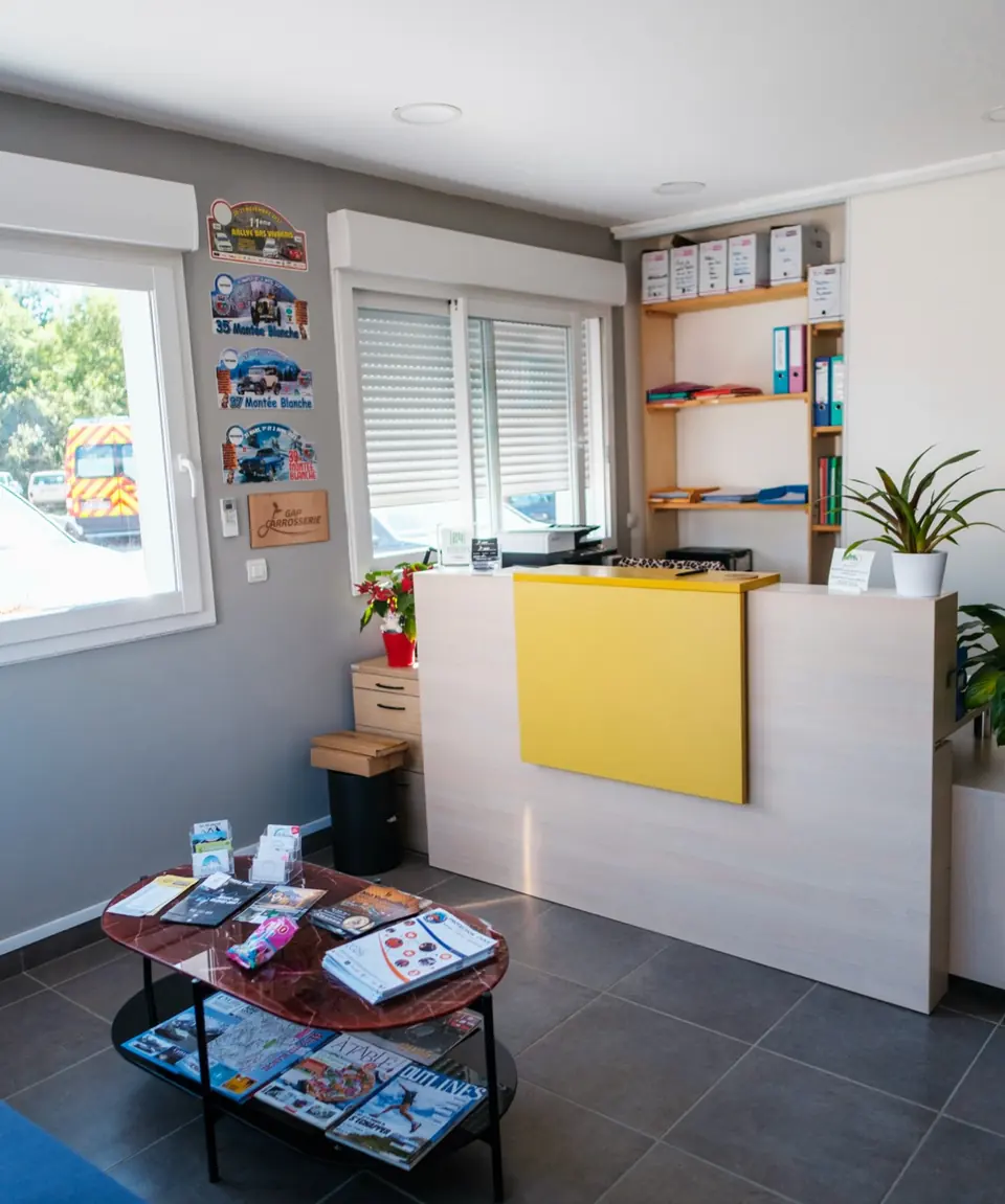 L’accueil de l’atelier : un comptoir jaune, des fauteuils et une table basse