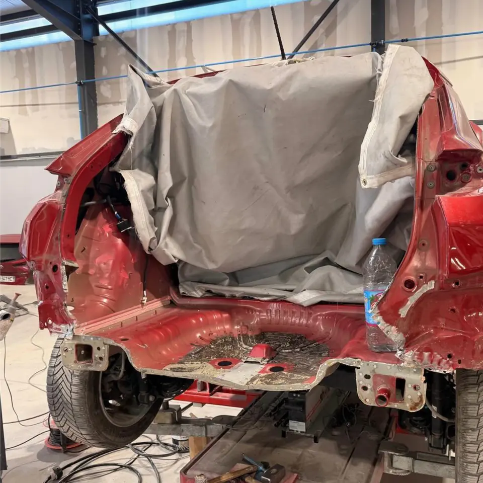 Avant : l’arrière d’un Hyundai Kona rouge arraché, bâché, à l’atelier